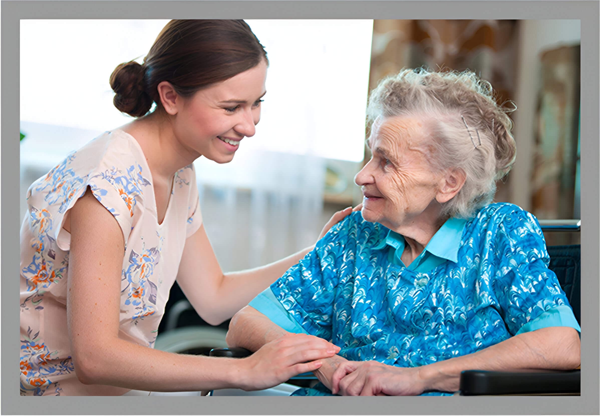 A woman and an old lady smiling at each other.