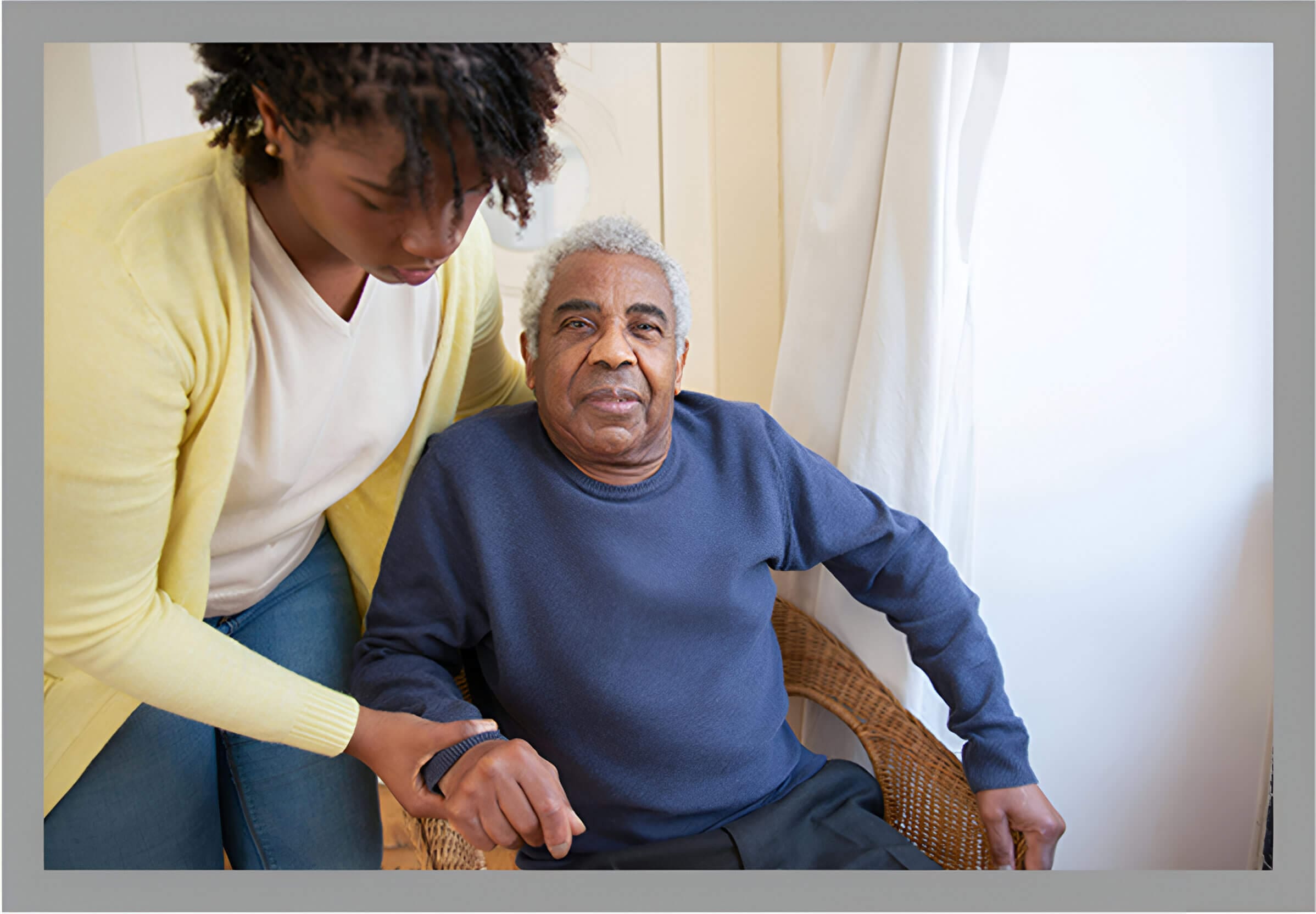 A woman helping an older man sit in his chair.